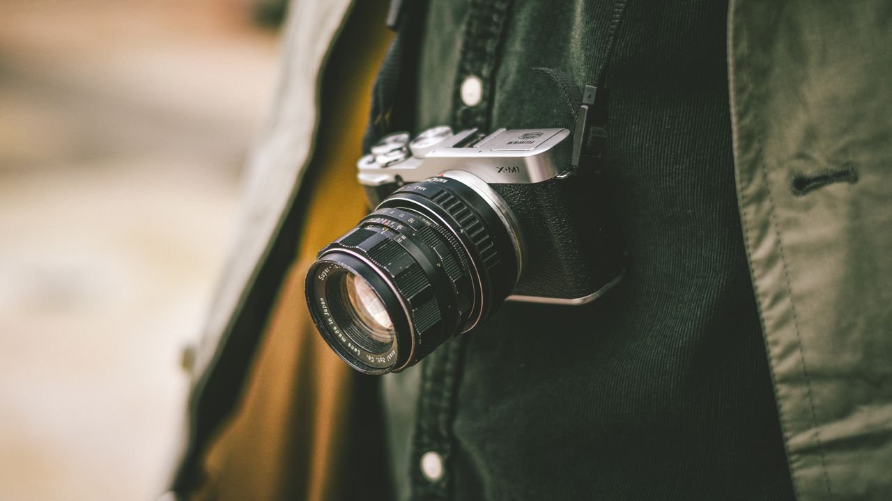 Services A classic vintage camera hanging by a strap, perfect for photography enthusiasts.