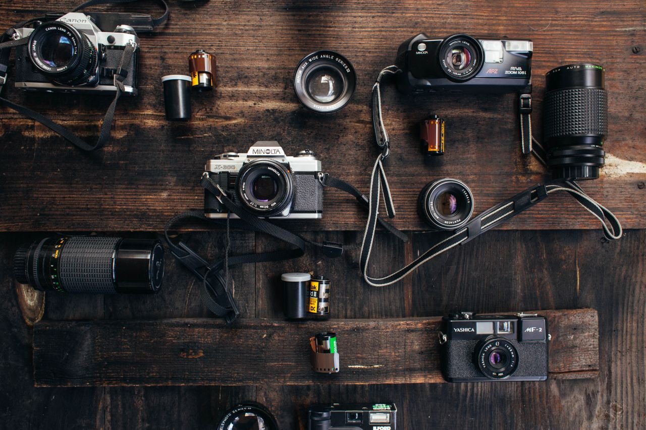 Services Overhead of retro photo cameras near various lenses and films on wooden surface